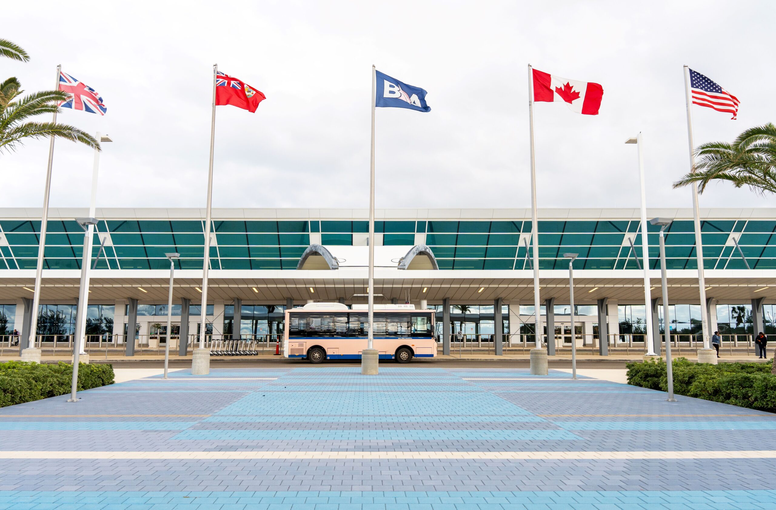 The entrance to LF Wade International Airport, flags flying and a waiting bus