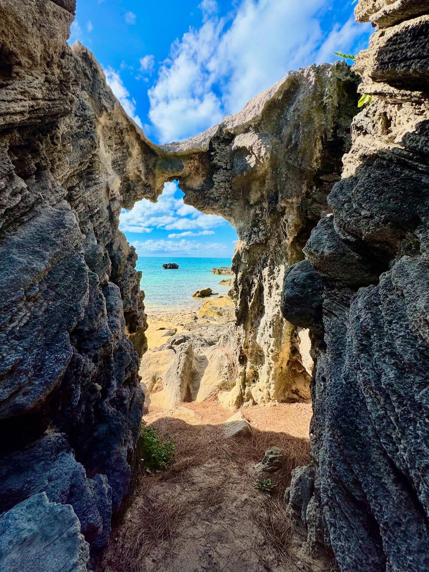 A natural limestone arch framing a turquoise Bermuda beach