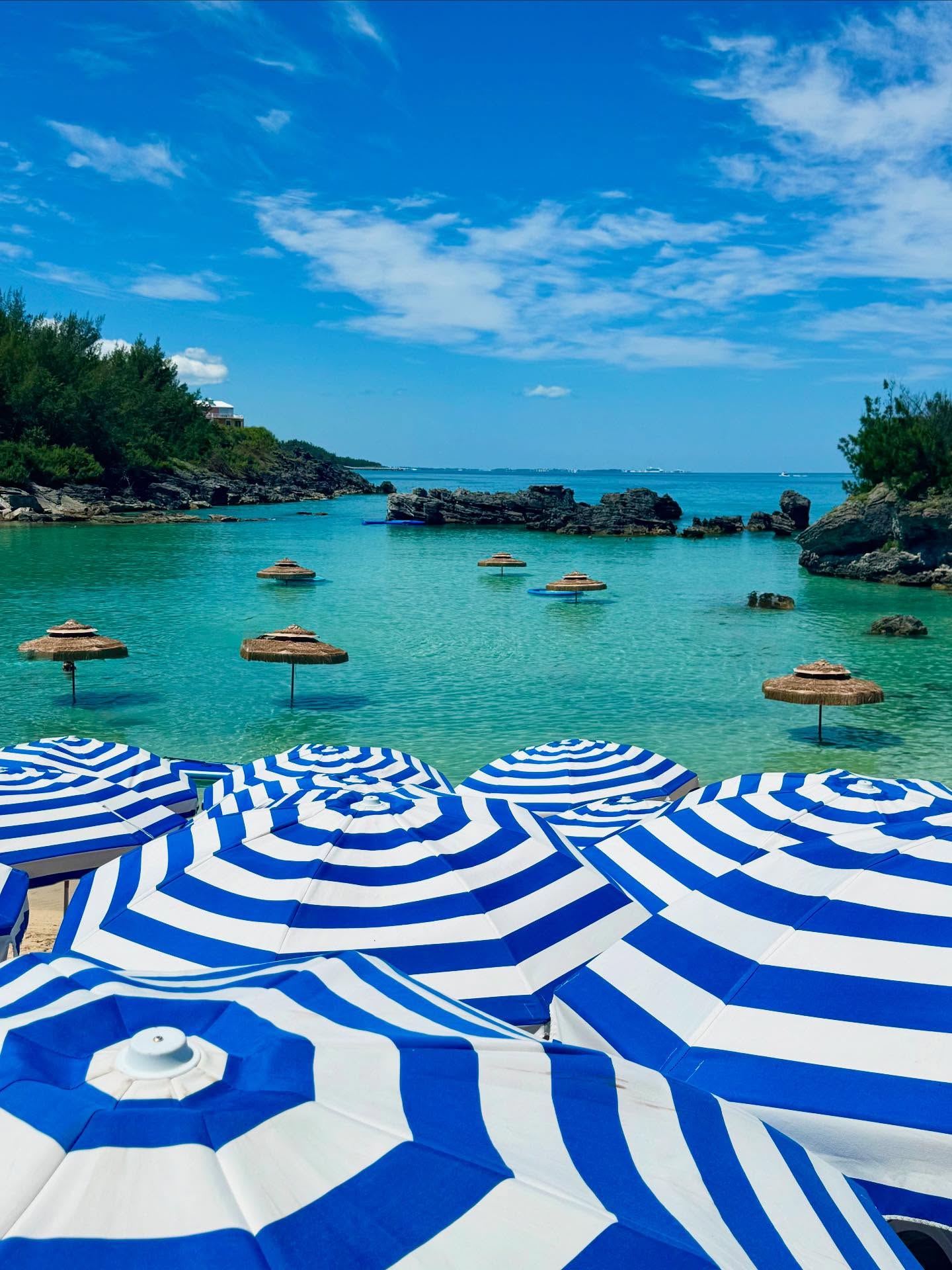 Blue and white striped parasols above a turquoise cove